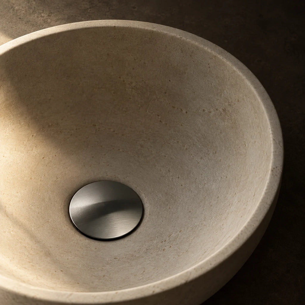 Bonde de Lavabo Clic-Clac en gris brossé, installée au fond d’une vasque en pierre