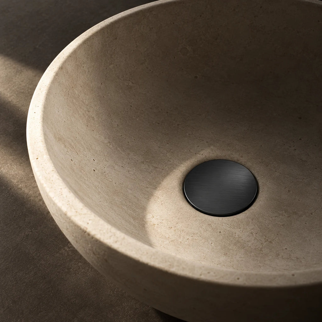 Bonde de Lavabo Clic-Clac en noir mat, installée au fond d’une vasque en pierre