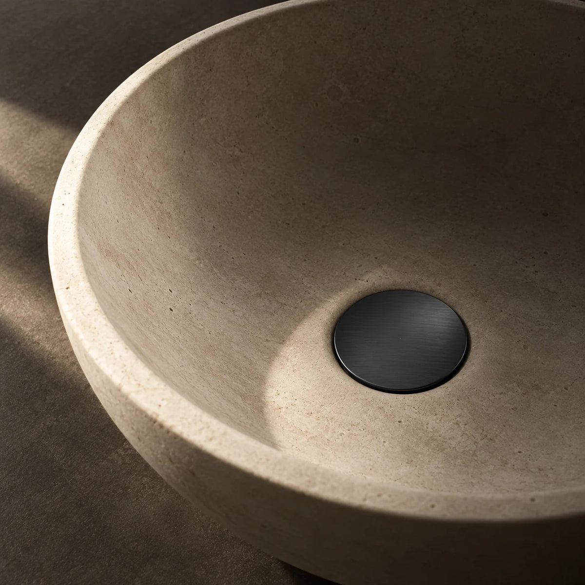 Bonde de Lavabo Clic-Clac en noir mat, installée au fond d’une vasque en pierre