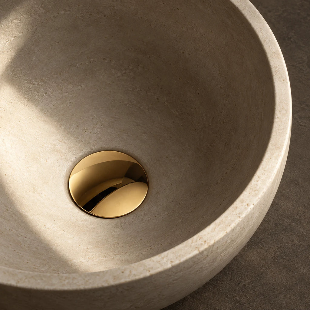 Bonde de Lavabo Clic-Clac en or brossé, installée au fond d’une vasque en pierre