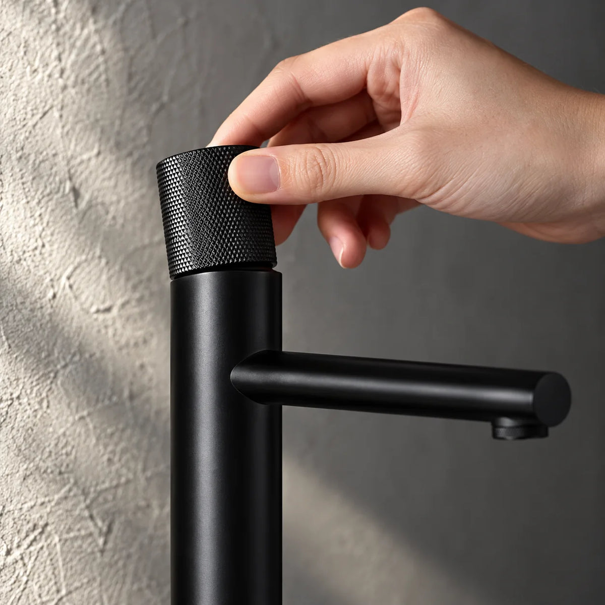 Main sur la commande du mitigeur lavabo bec haut xl, vasque à poser en noir mat