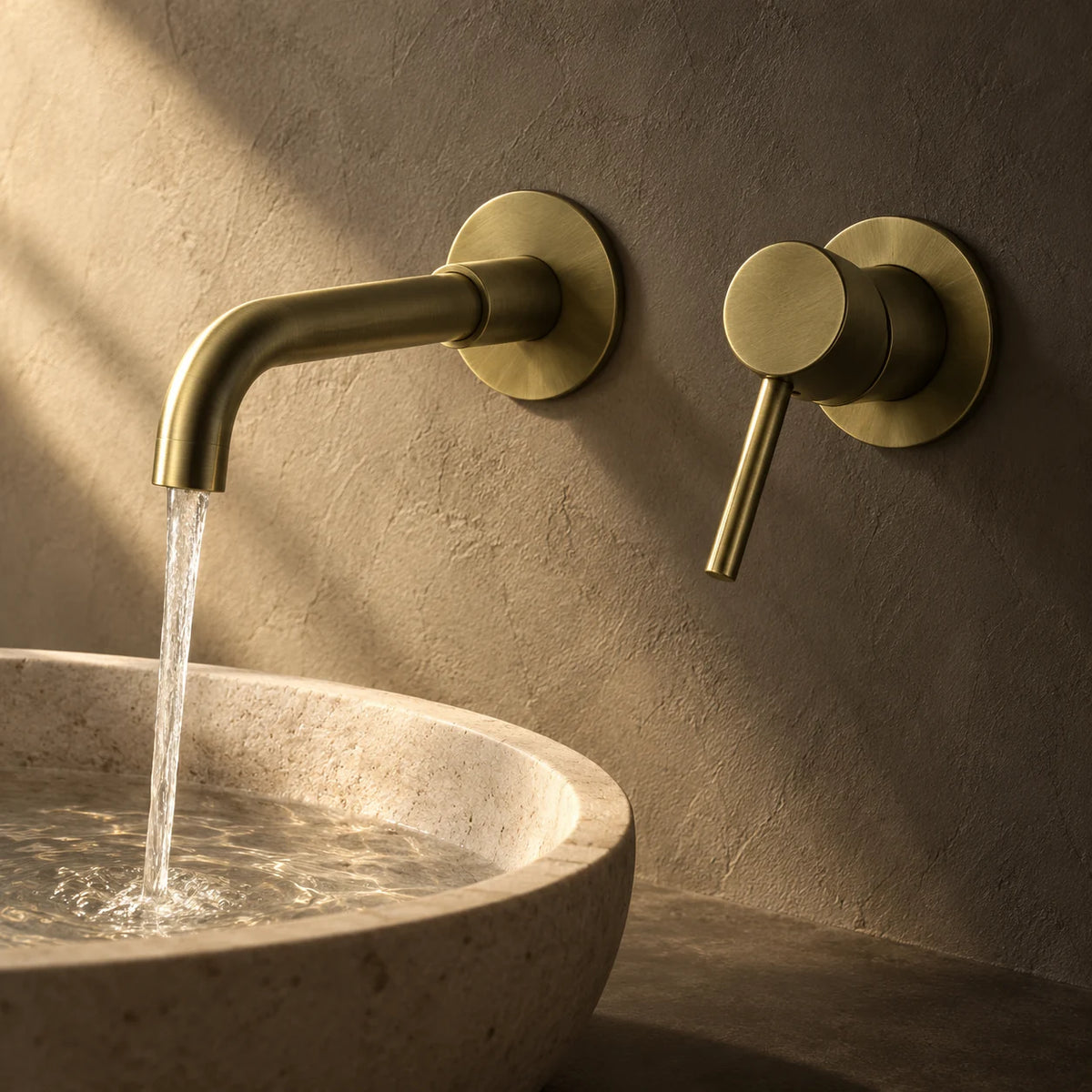 Mitigeur Lavabo Encastré Mural en or brossé, installé au-dessus d’une vasque en pierre